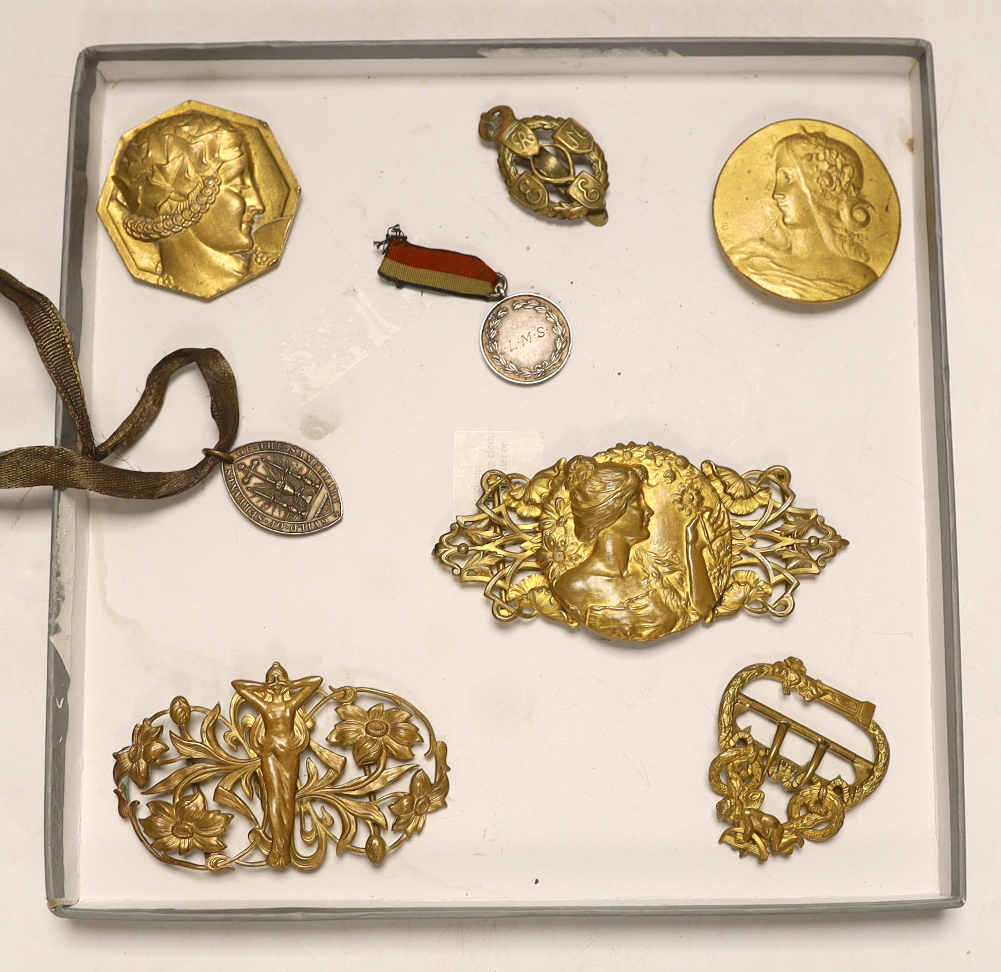 Assorted gilt metal Art Nouveau figural buckles, one signed. F Lasserre, similar hexagonal Art Deco brooch signed P Turin, a 1920’s silver sports jewel etc. largest 11cm wide